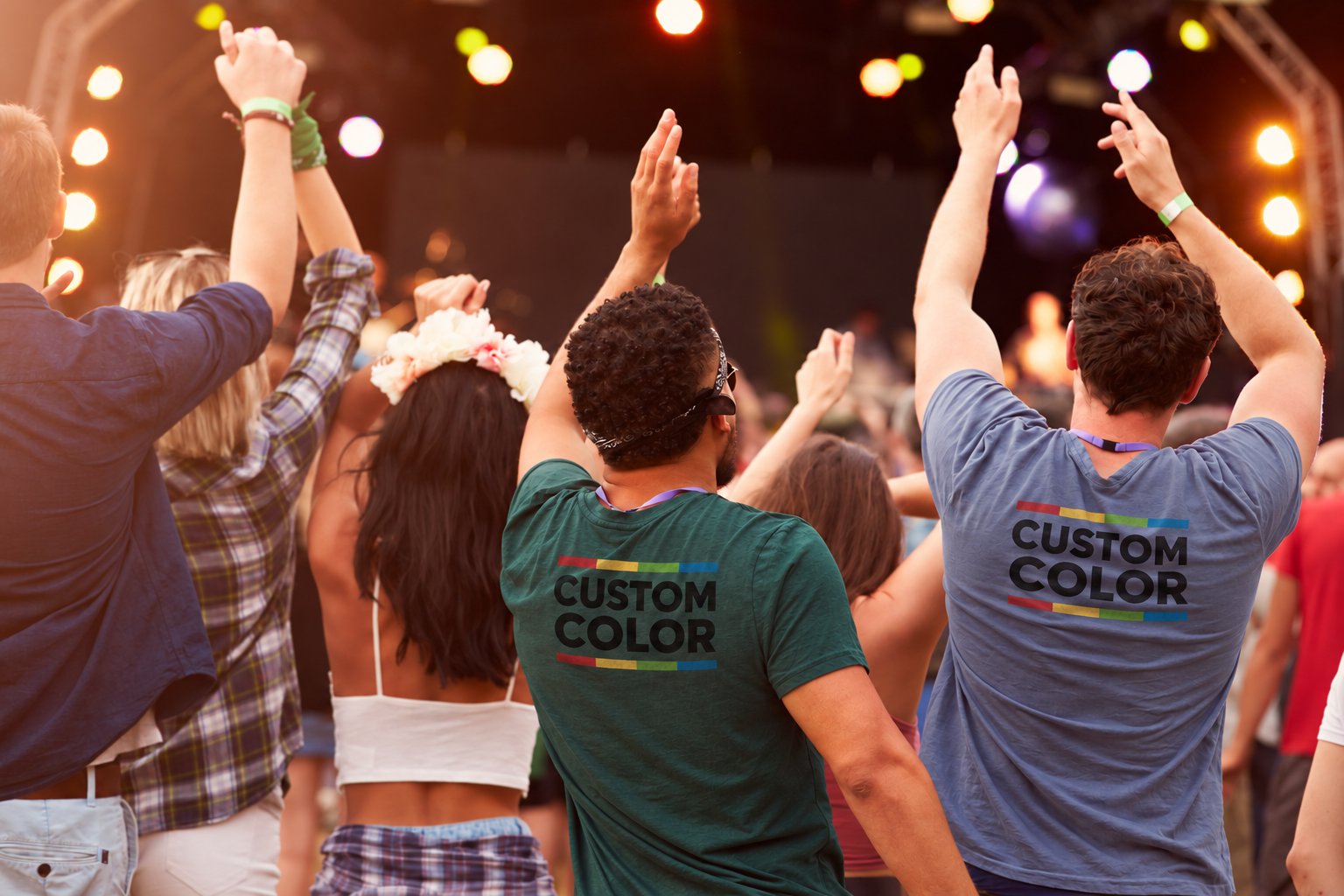 Friends at a concert seen from behind, two of them in tees printed with the Custom Color logo