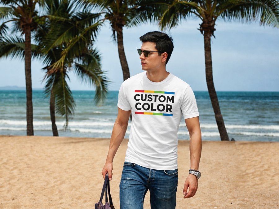 White t-shirt printed with the Custom Color logo, palm trees and ocean behind