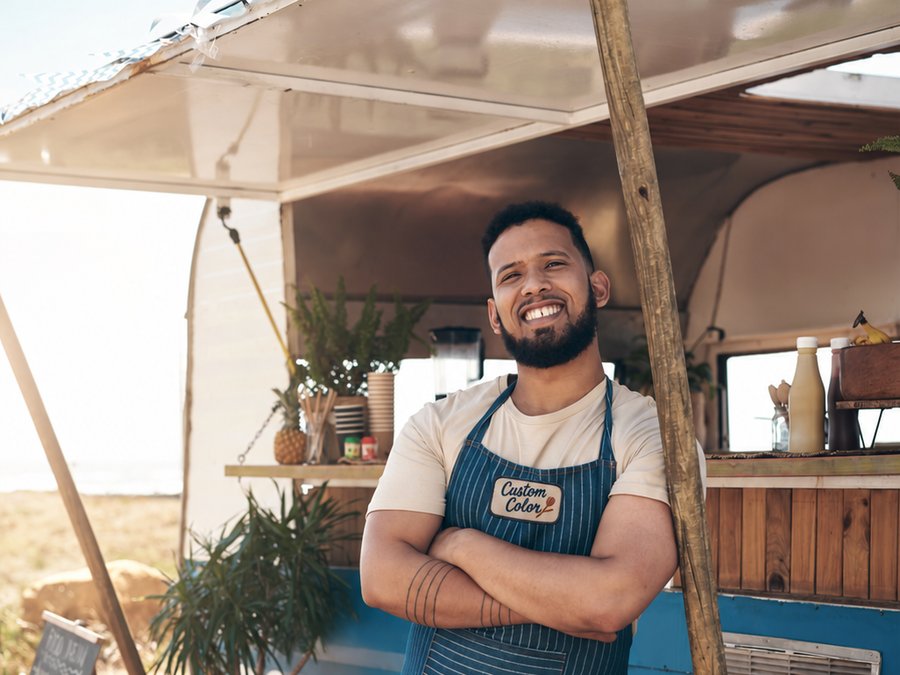 Food truck owner in an apron over a tee printed with the Custom Color logo