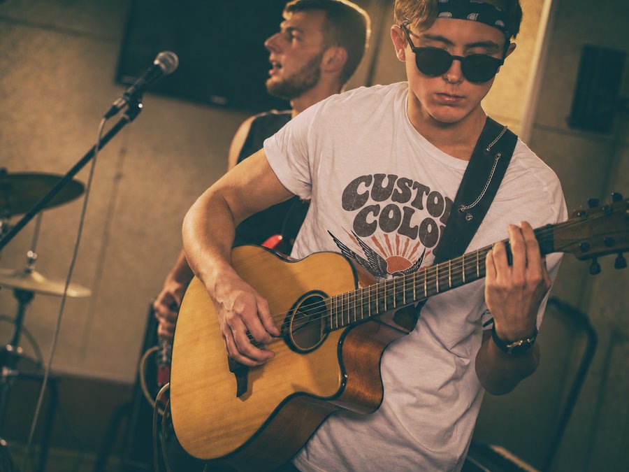 Guitarist at rehearsal wearing a white tee printed with a retro Custom Color design