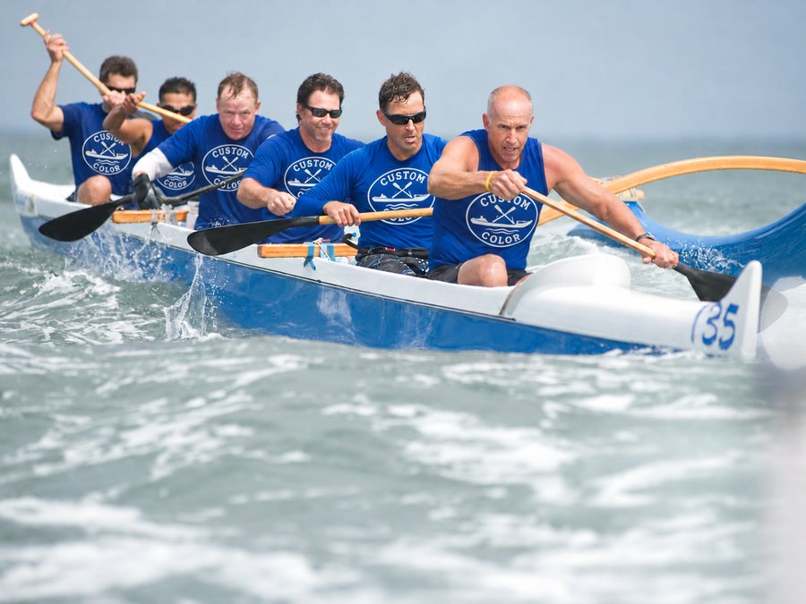 Outrigger canoe crew paddling in matching blue tees